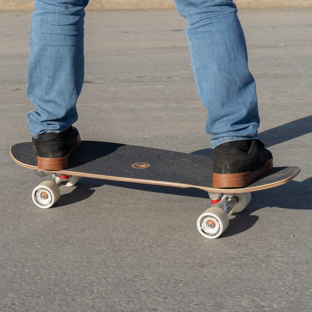 Füße in Sneakern auf dem Surfskate Wood Wave, Nahaufnahme beim Fahren