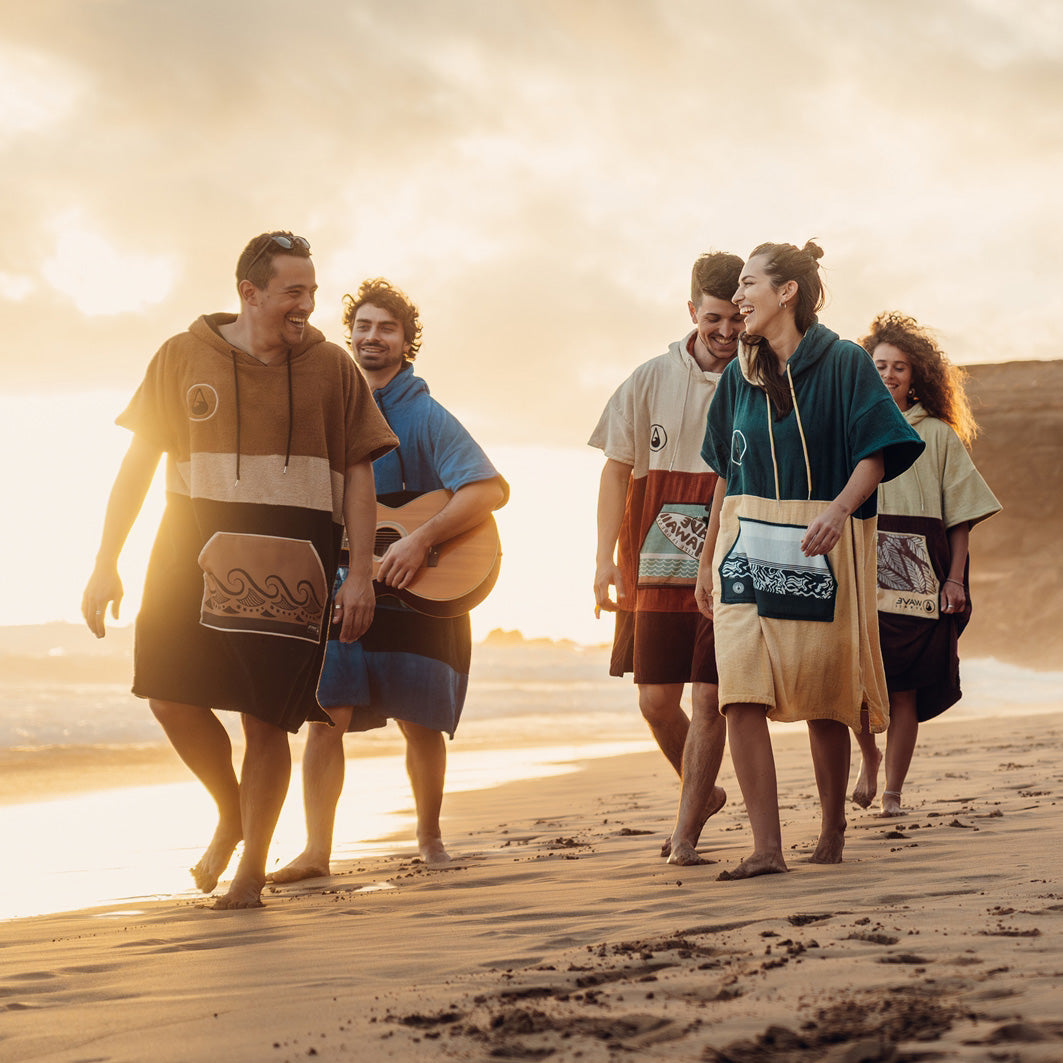 Freunde in Surf Ponchos spazieren bei Sonnenuntergang am Strand, Ponchos und mehr von WAVE HAWAII
